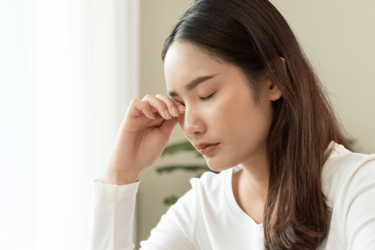 a woman rubbing her eye due to discomfort