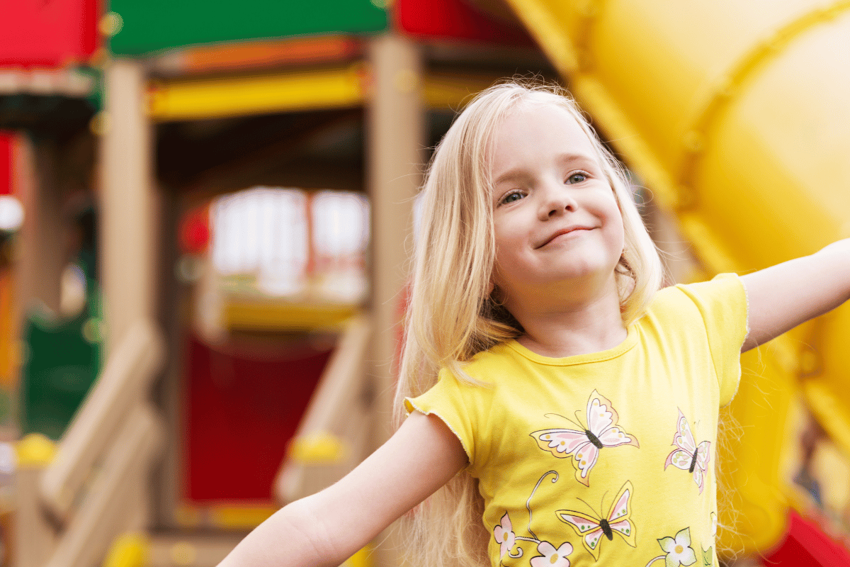 a little girl playing outside at a playground