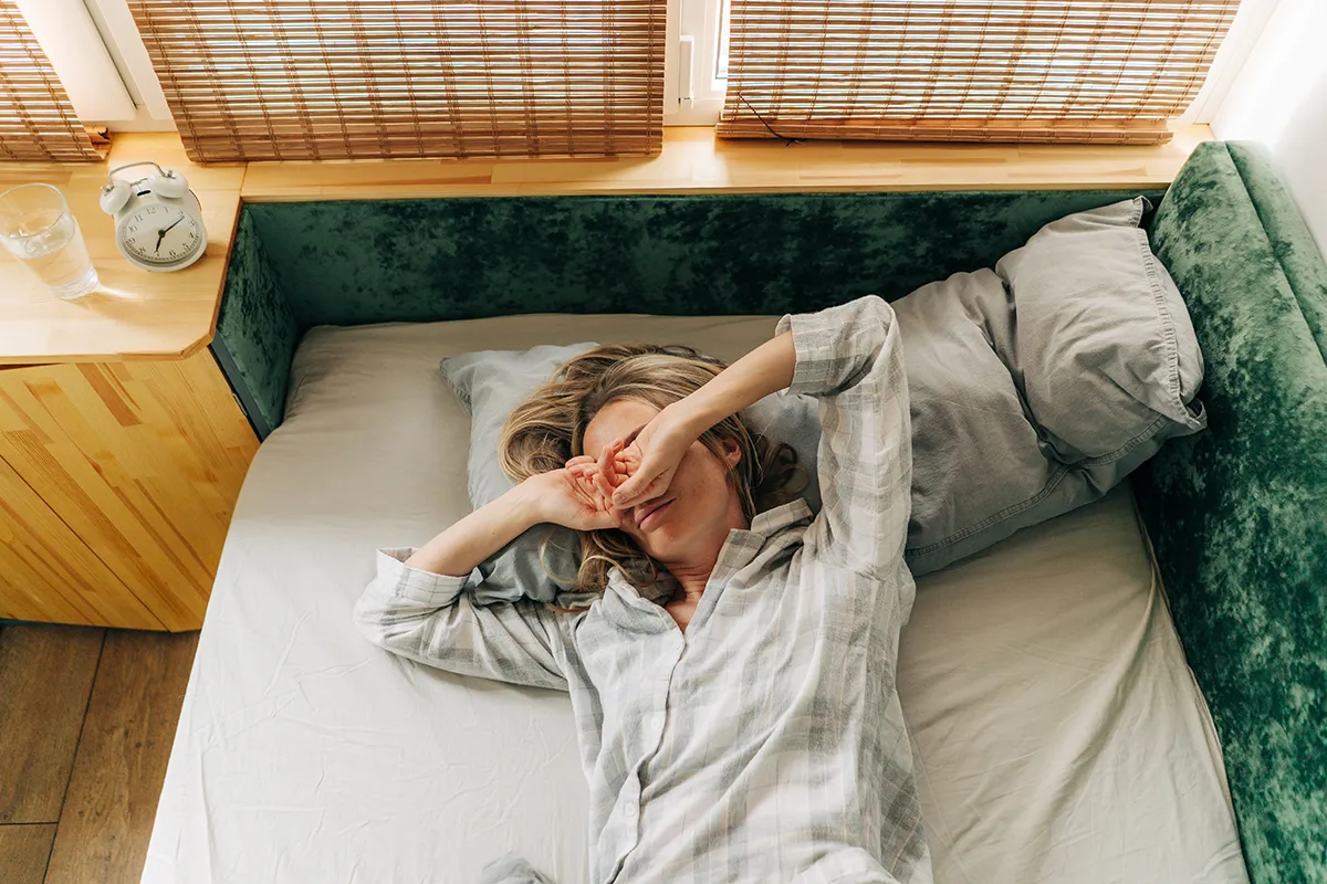 a woman in bed rubbing her eyes after waking up