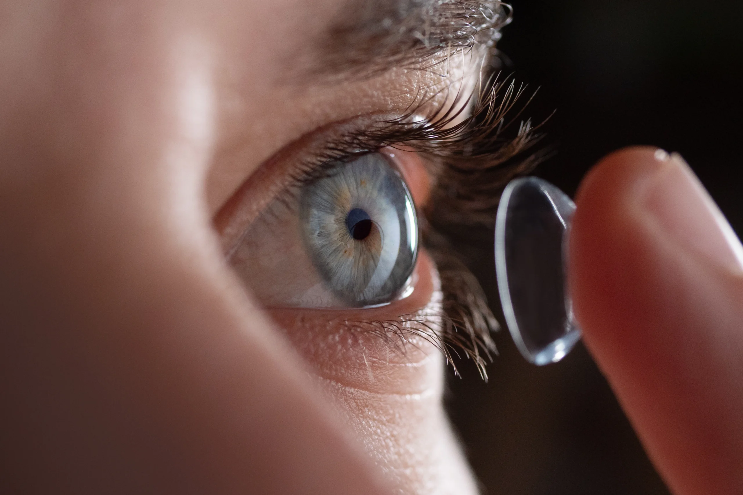 A close up picture of a woman putting in a contact lens.