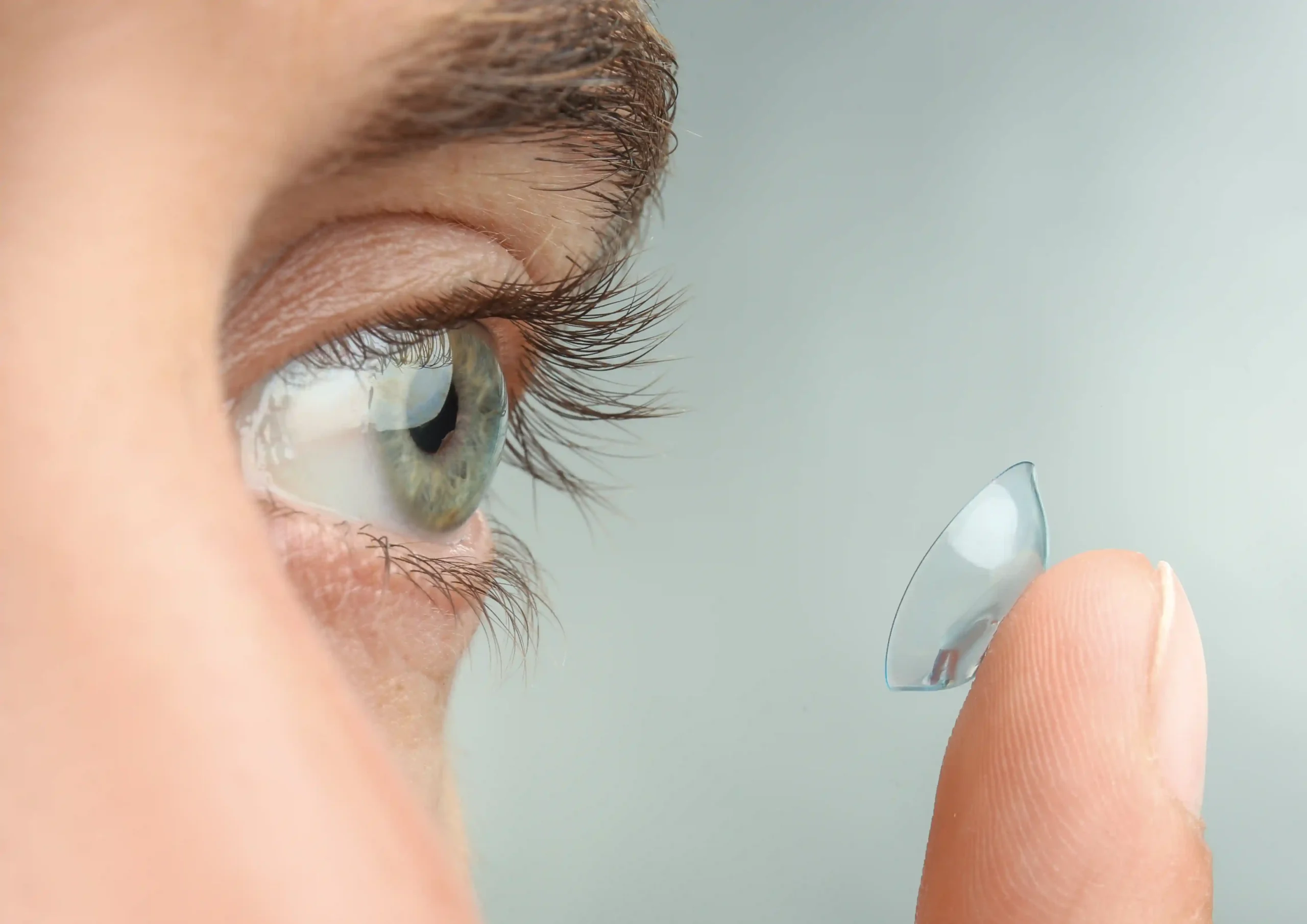 person placing contact lens into eye